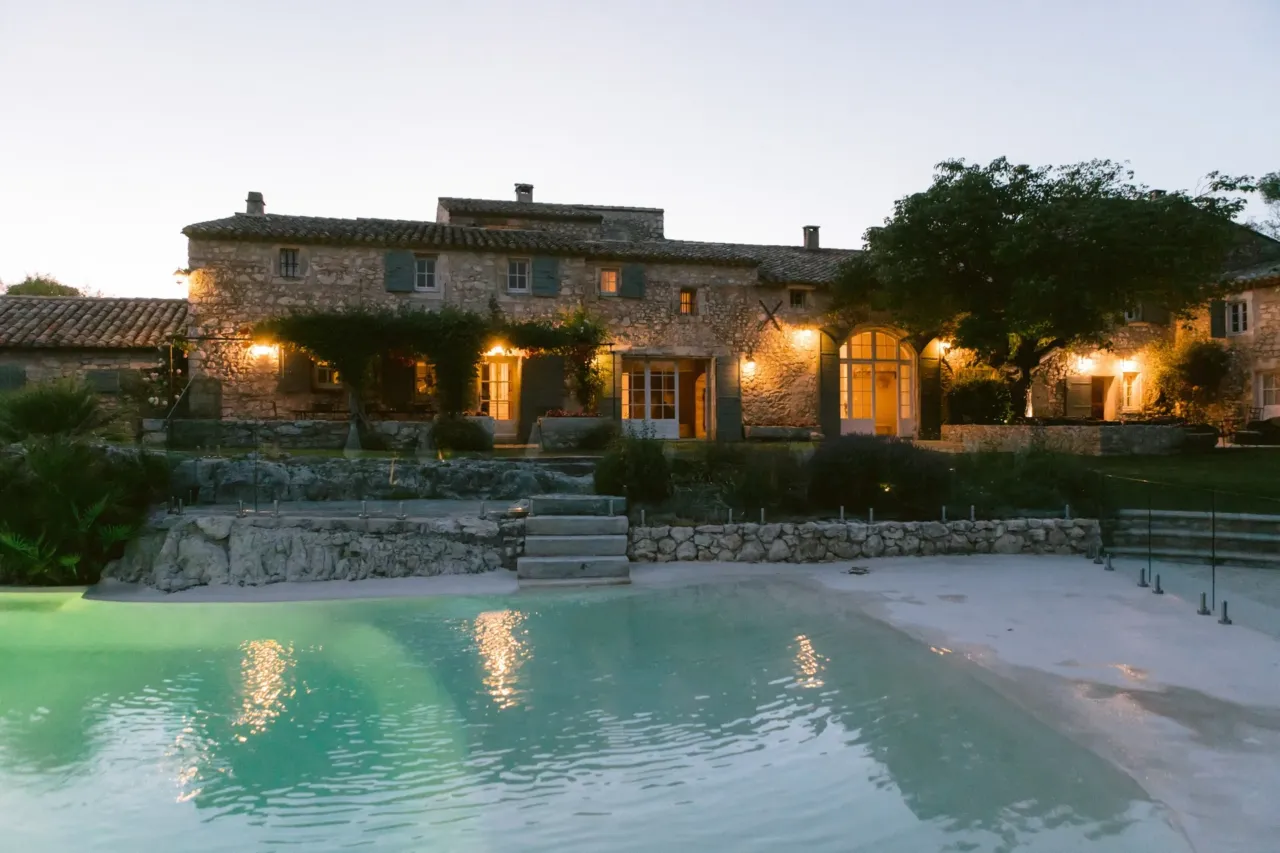 Mas en Provence en pierre au bord d'une piscine éclairée.