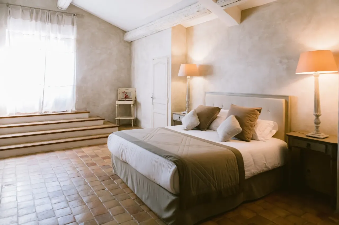 Domaine Saint Rémy de Provence avec une chambre lumineuse avec lit double et lampes beige.