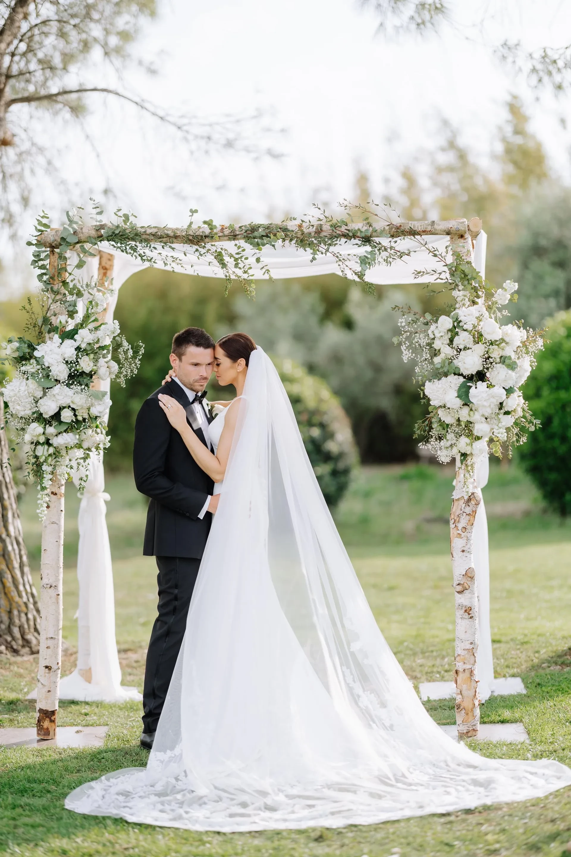 Mariés sous une arche florale élégante dans un jardin.